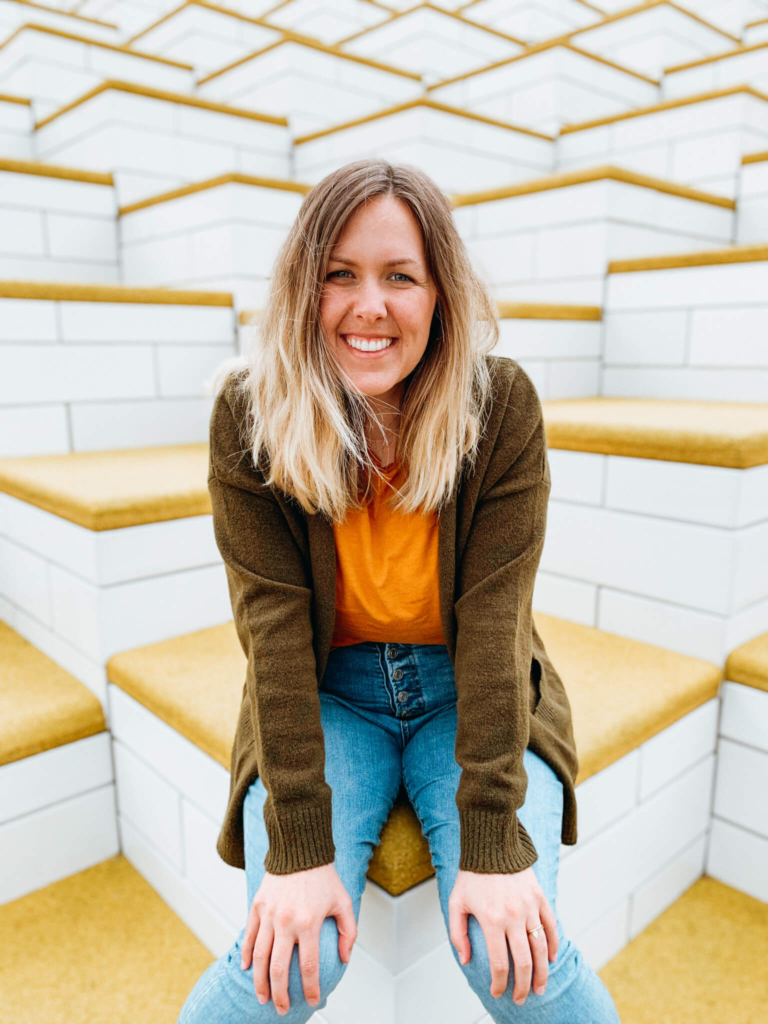 Woman sits on yellow and white stairs at The LEGO House in Denmark