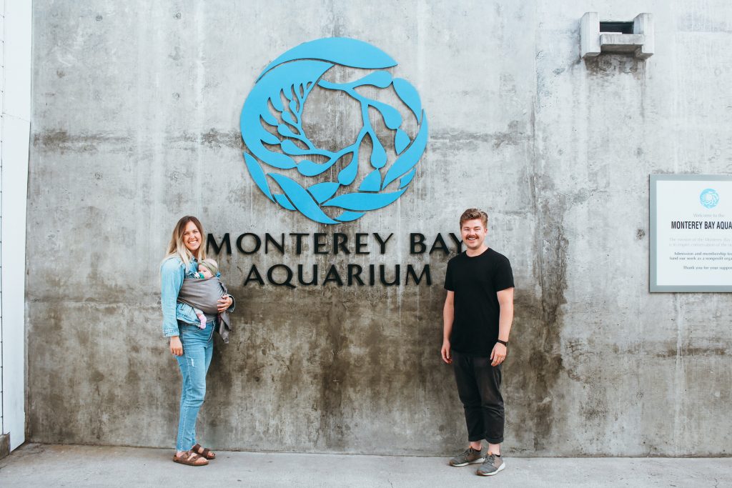 woman, child and man in front of sign that says Monterey Bay Aquarium