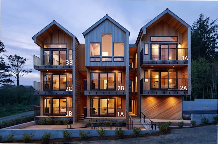 3-story building with multiple balconies lit up at dusk