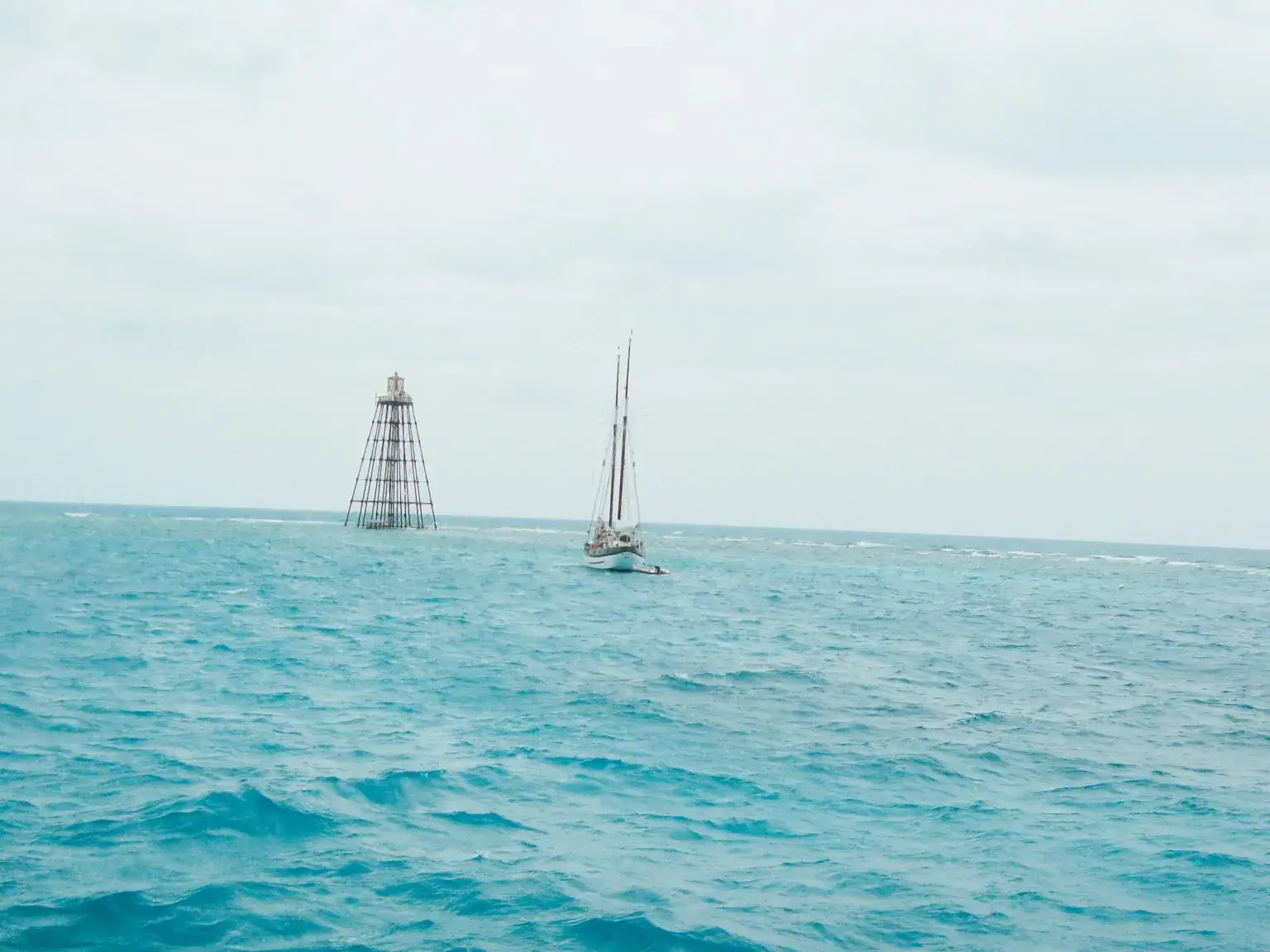 Sandbar Key lighthouse on the water with a sail boat