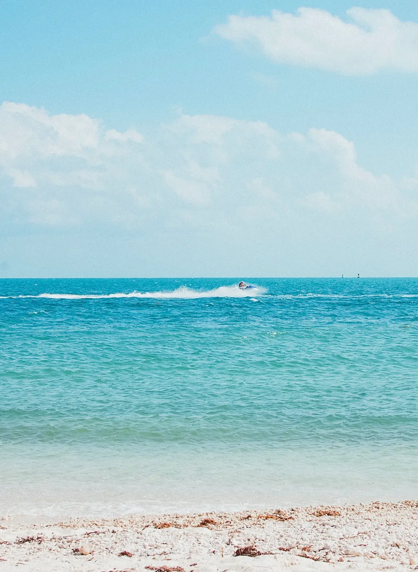 Bright blue ocean water with a jet ski in the distance