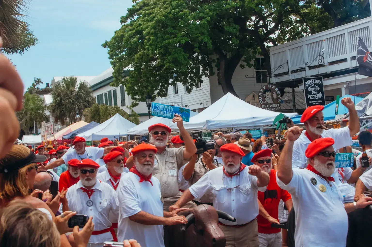 Large parade of men with white beard and shirts and red hats and kerchiefs. Attending the Hemingway Festival is one of the top things do in Key West