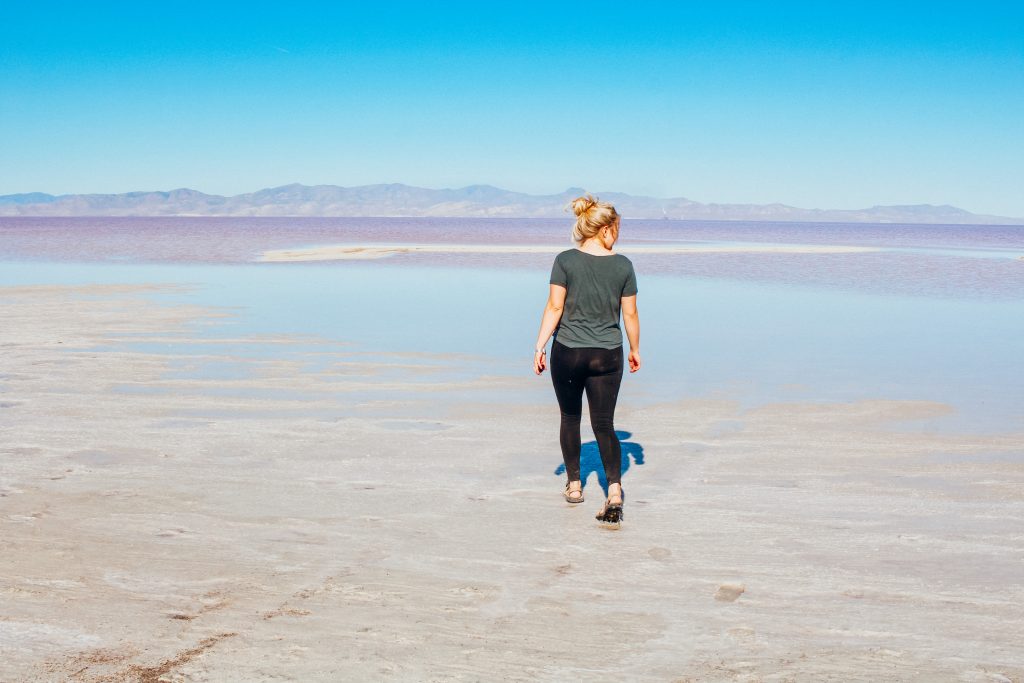 Woman walking towards pink lake in Utah which is one of Utah's hidden gems