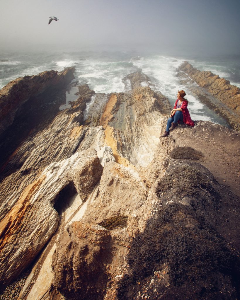 Woman on rocks in ocean at Montaña de Oro State Park in California