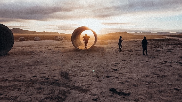 Silhouette of person in large cement tunnel during sunset