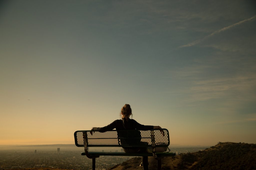 Women on a hike sitting on a bench at sunset overlooking Los Angeles