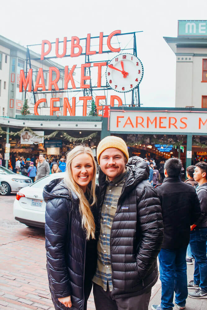 A woman and man stand in front of building with sign on top saying 'Public Market Center'