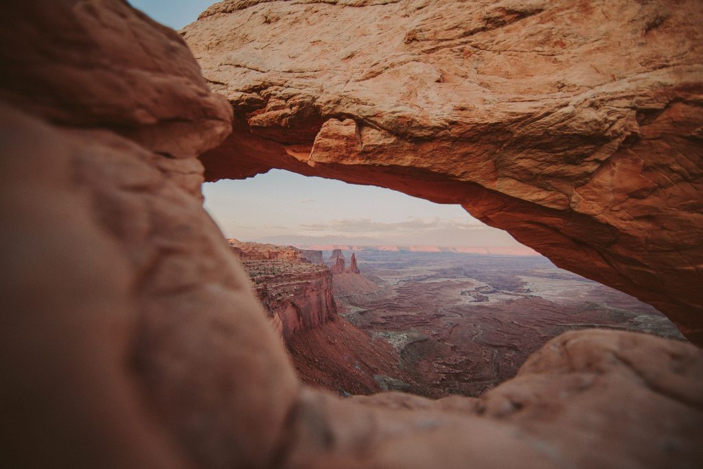 Close up of red sandstone rock with view of desert valley floor below