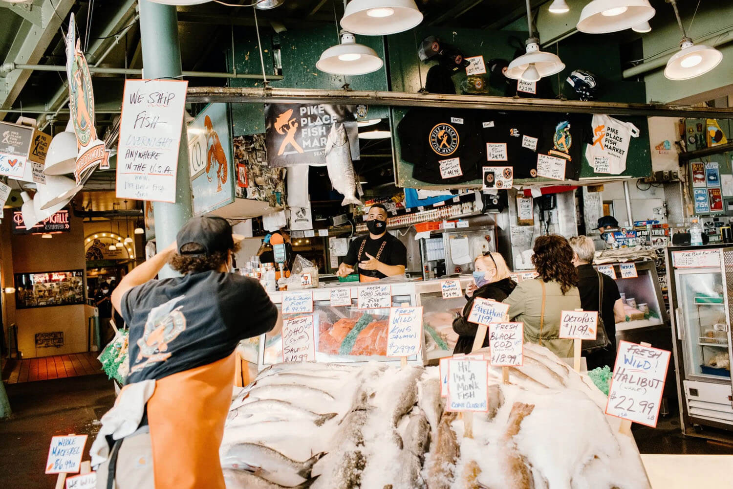 Worker at fish stand tosses large fish to another worker