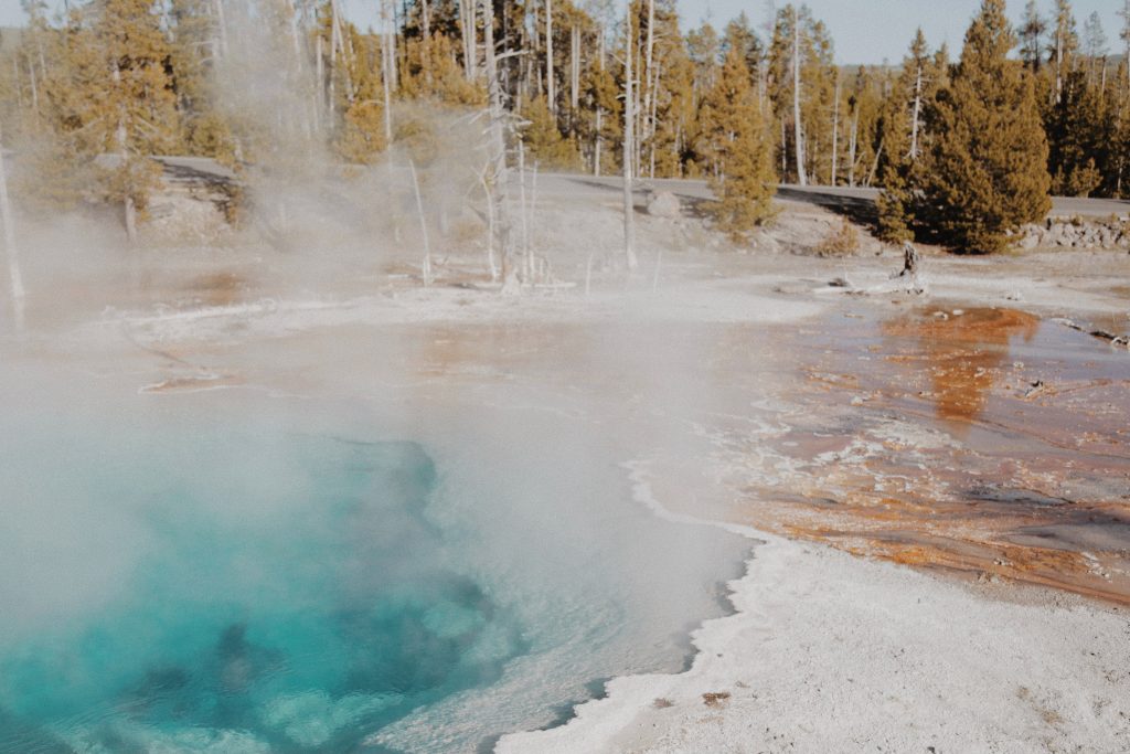 Natural clear pool of bright blue water with steam rising from it
