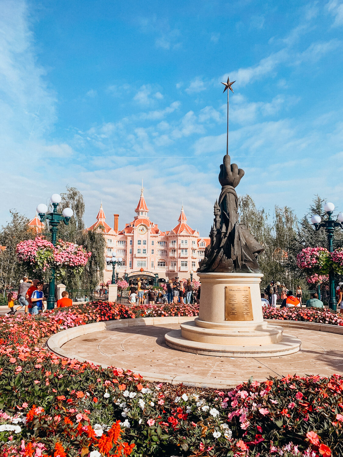 Statue of Mickey's hand with a wand in front of ornate pink building at Disneyland Paris