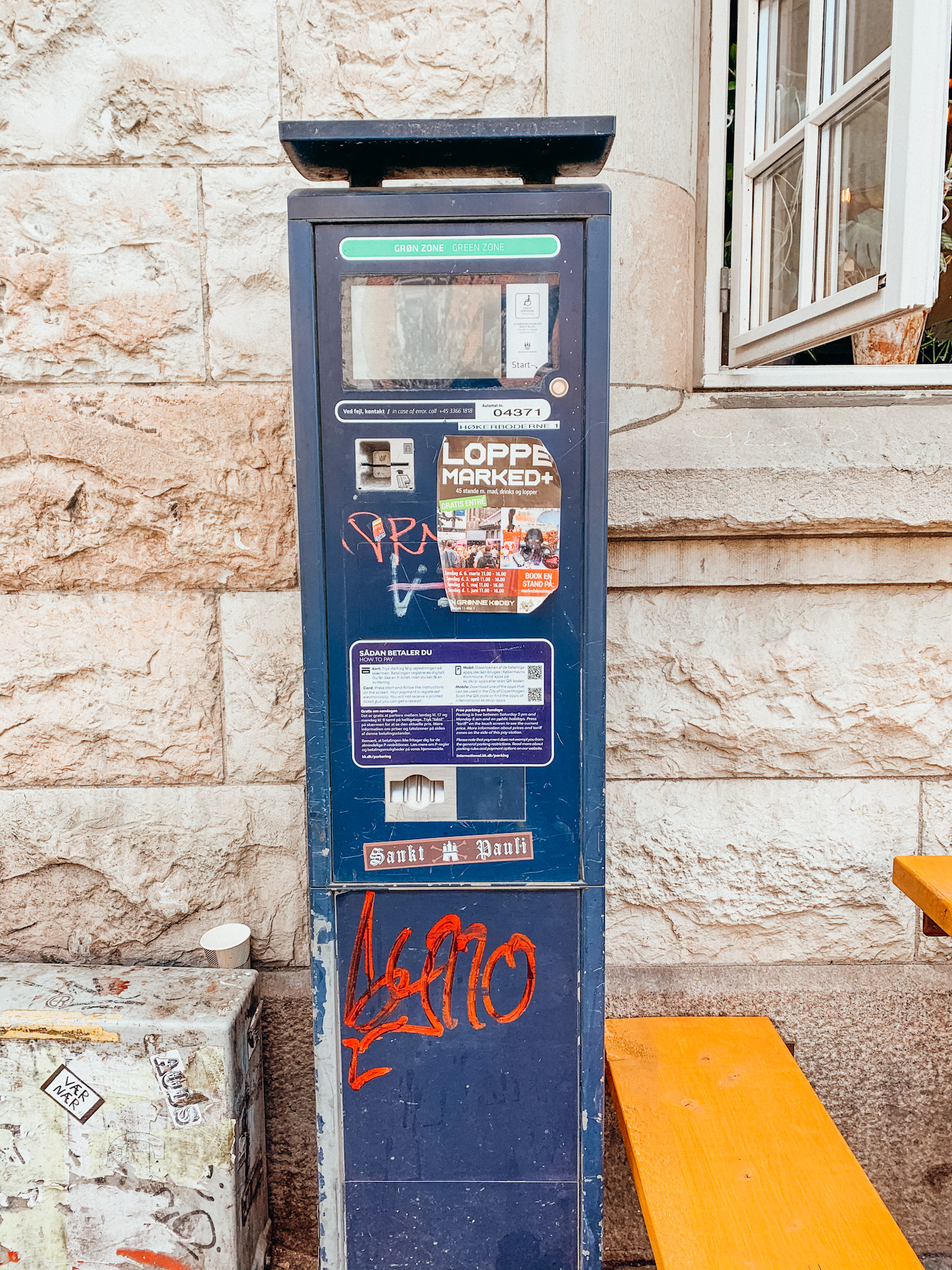 A blue parking meter against a brick wall in Copenhagen