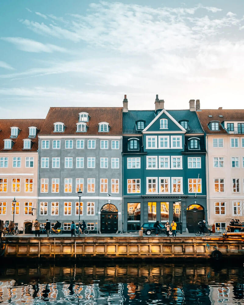 Blue and white buildings with many windows line a canal in Copenhagen