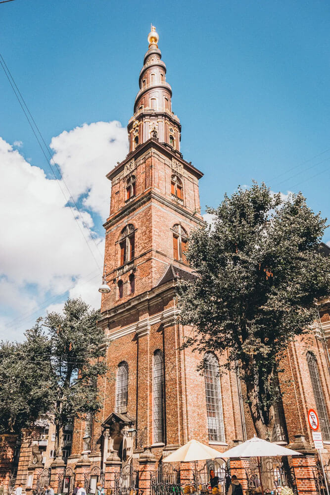 Tall, brown brick church with golden spiral spire