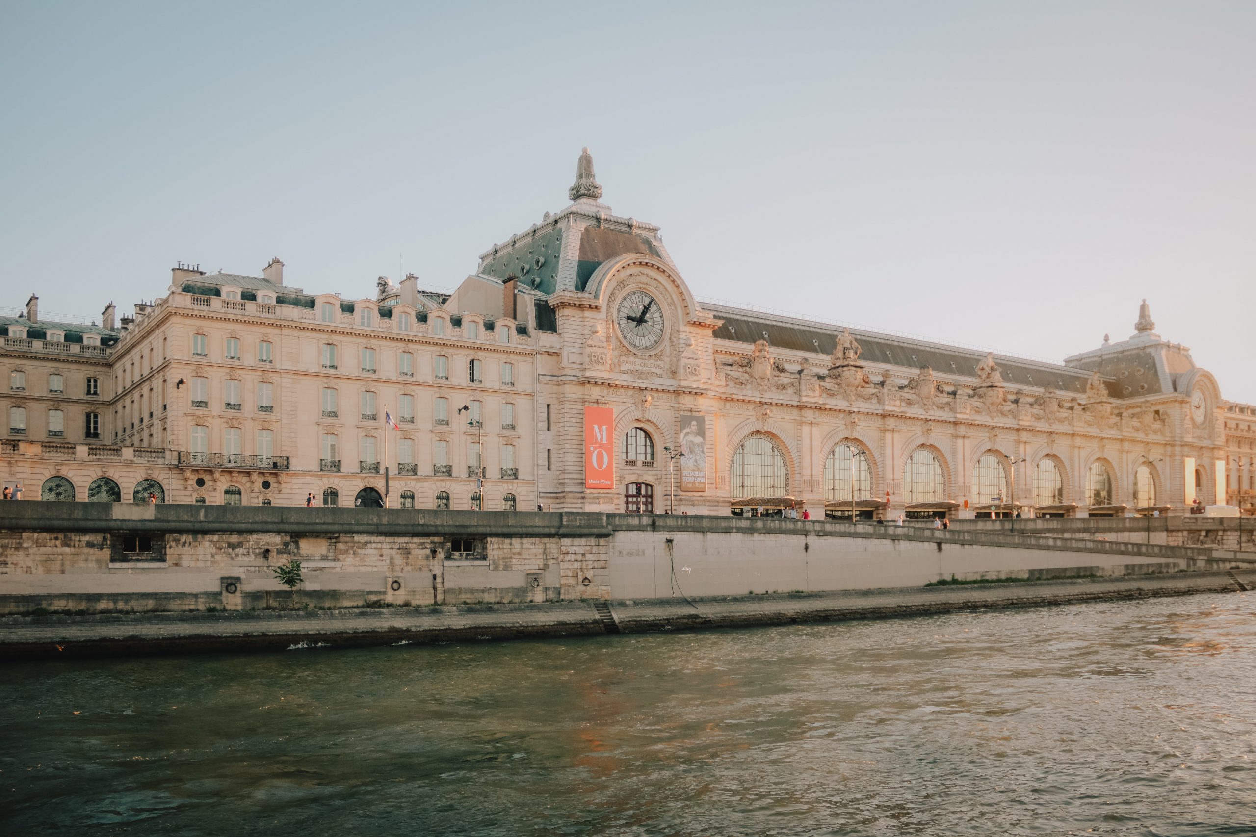 Large white building with large clock along the Seine River in Paris