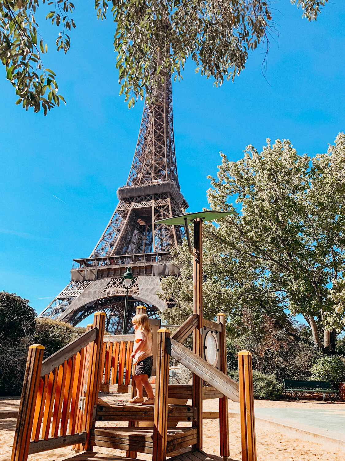 Child plays on wooden playground at the base of the Eiffel Tower in Paris