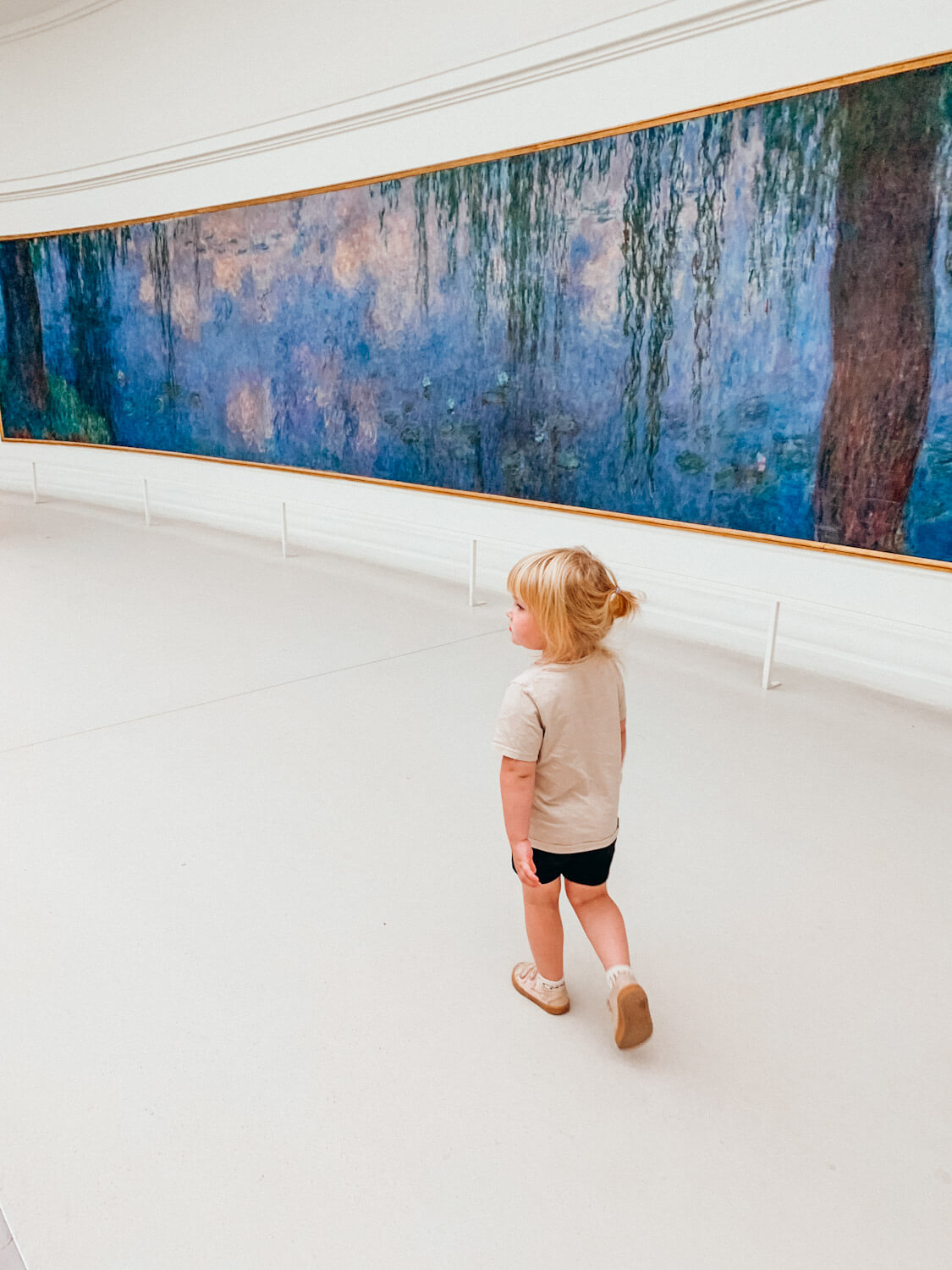 Child walk past painting at Musee de l'Orangerie in Paris