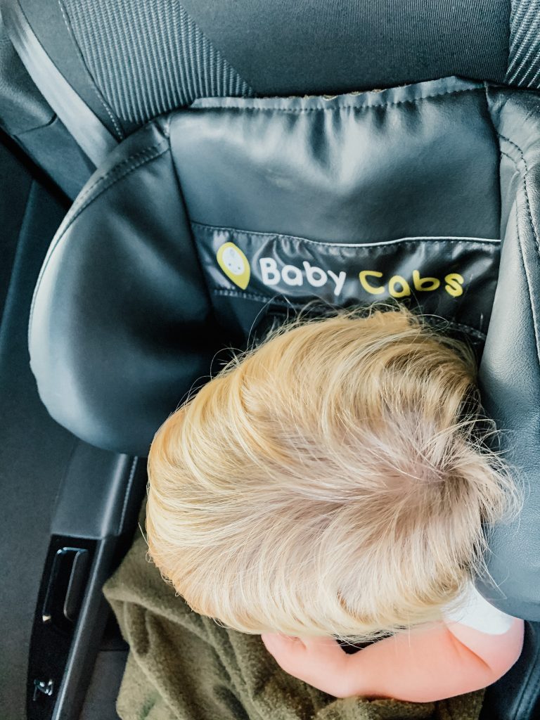 Child sits in black car seat in a taxi in Paris