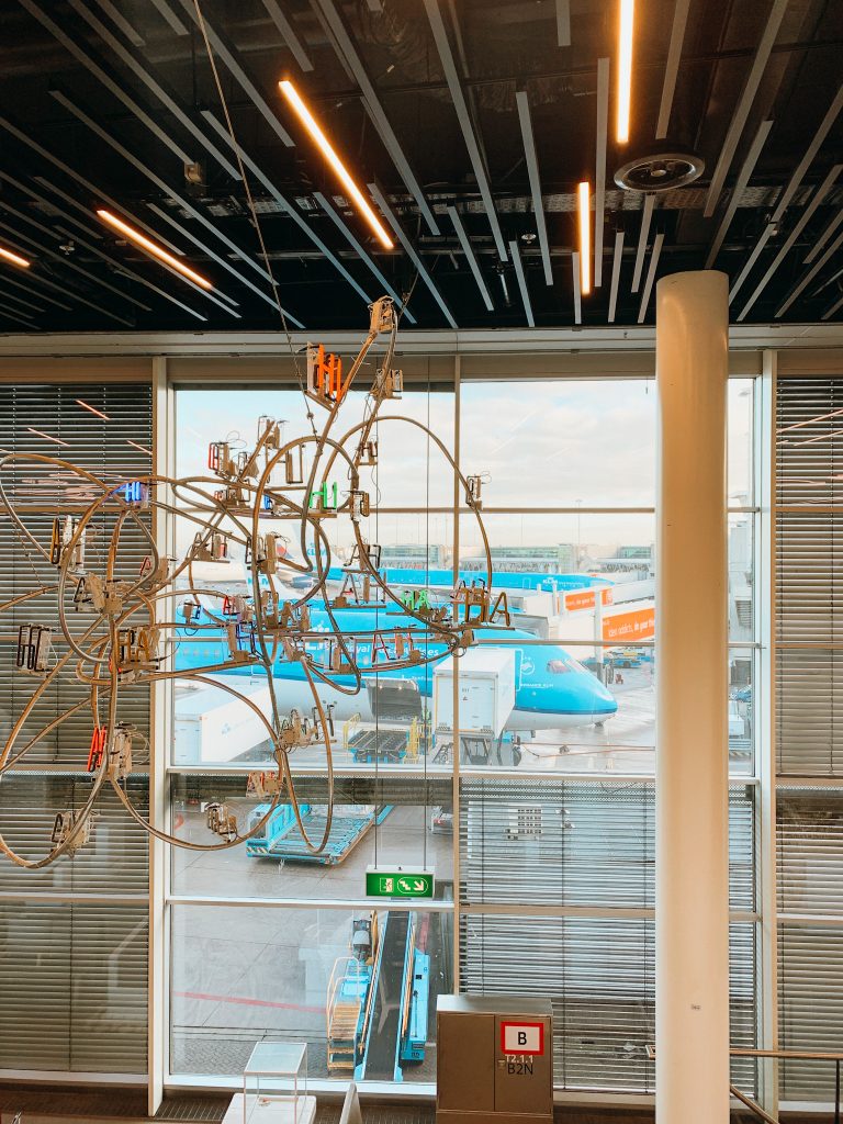 Hanging sculpture in front of large windows looking out to airplanes on a tarmac