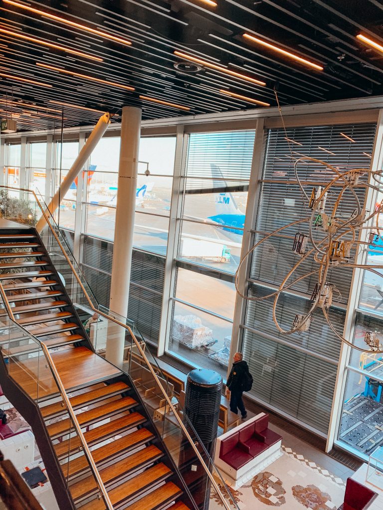Wooden stairs in front of large windows looking out to airplanes parked on the tarmac