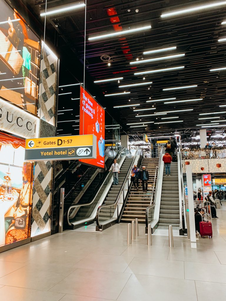 Signs hang from ceiling in front of escalators in an airport
