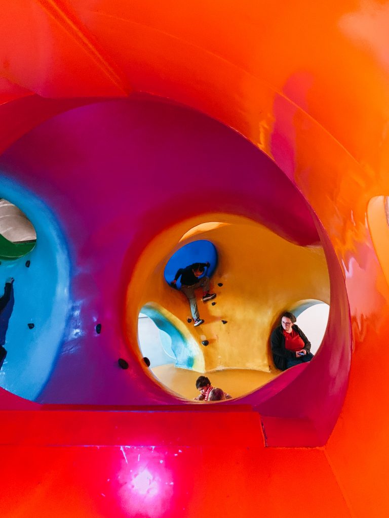 Colorful interior of playground with rock climbing holds and people climbing