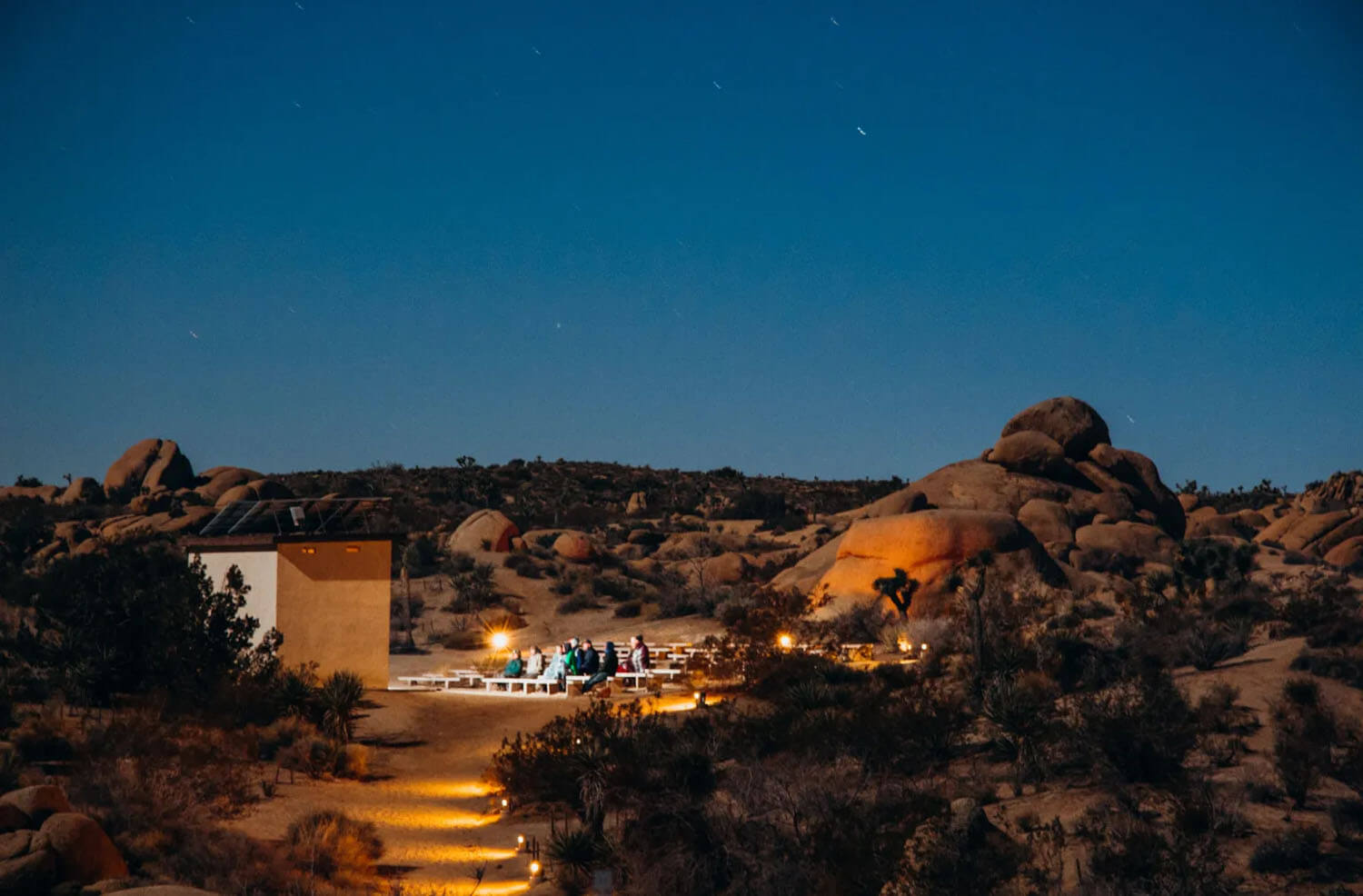 Nightime view of benches in the desert surrounded by large boulders