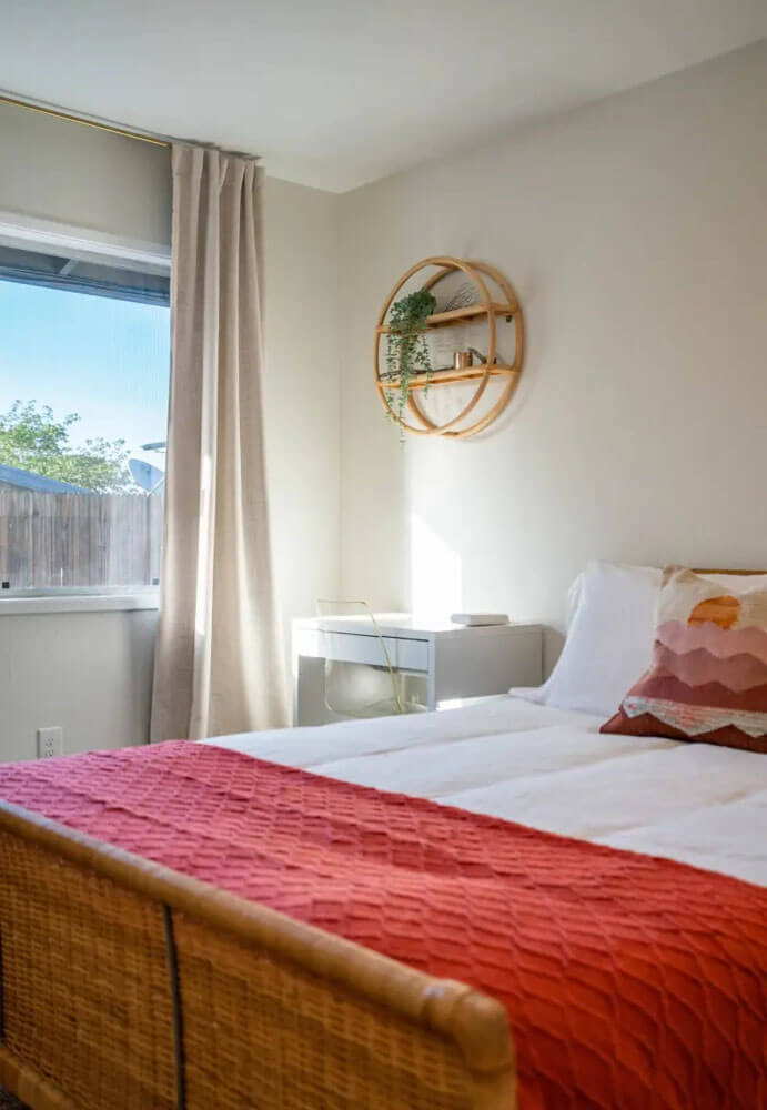 White bed with red blanket and a pink pillow