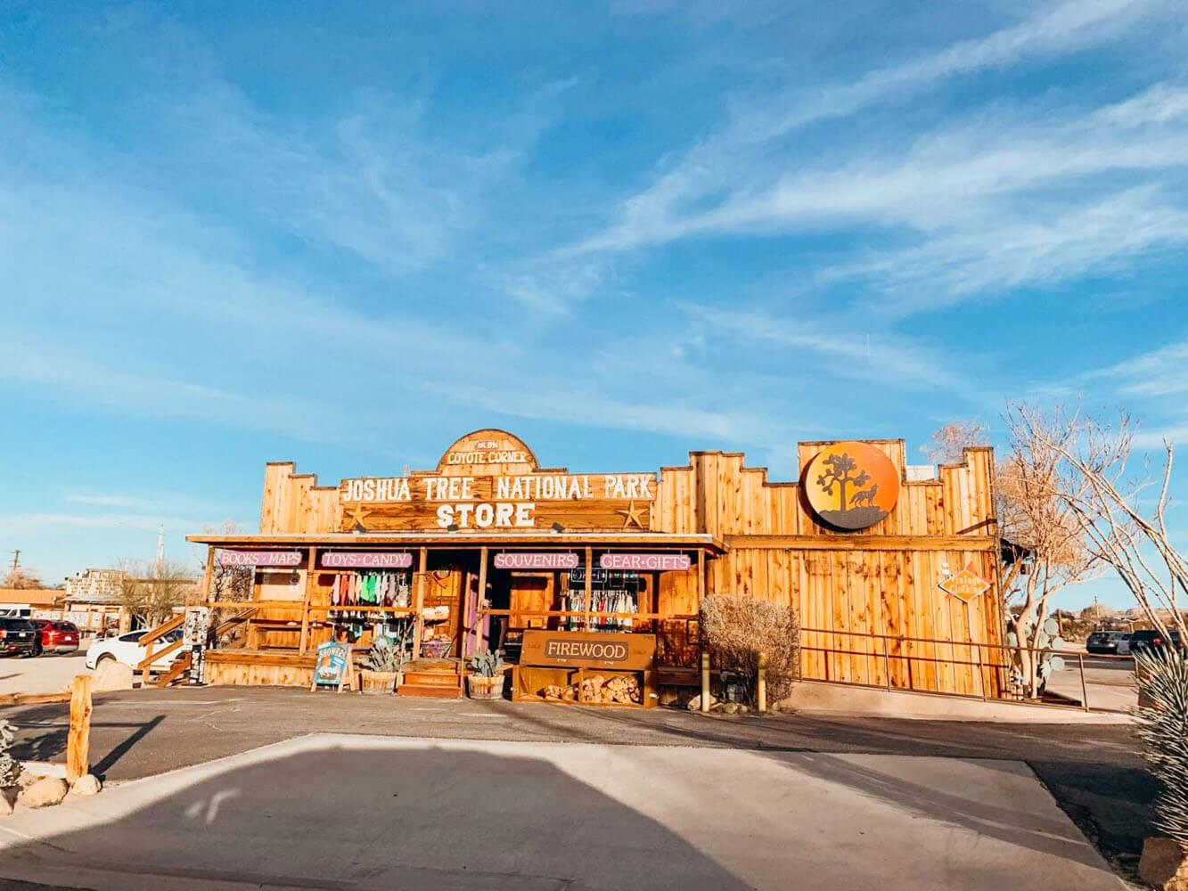 Wooden building with purple signs and a white sign that reads 'Joshua Tree National Park Store'