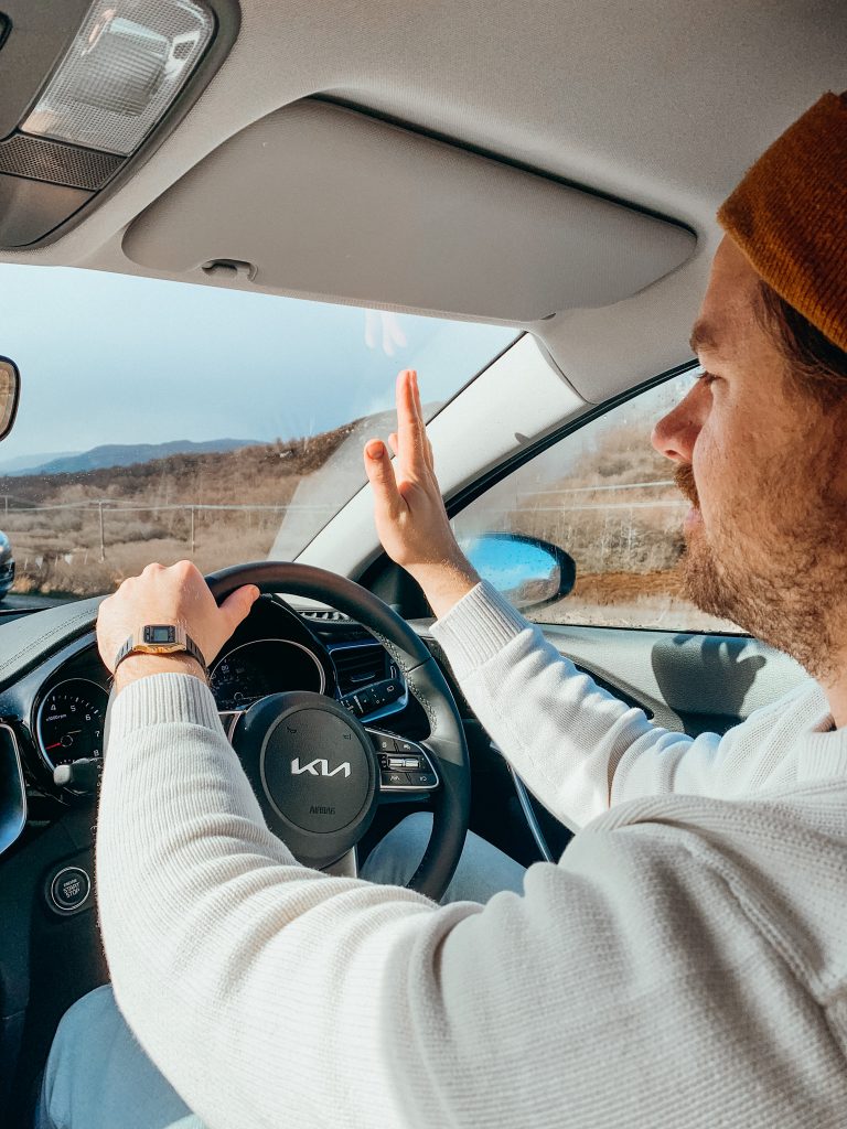 Man sitting in the drivers seat waving to a passing car