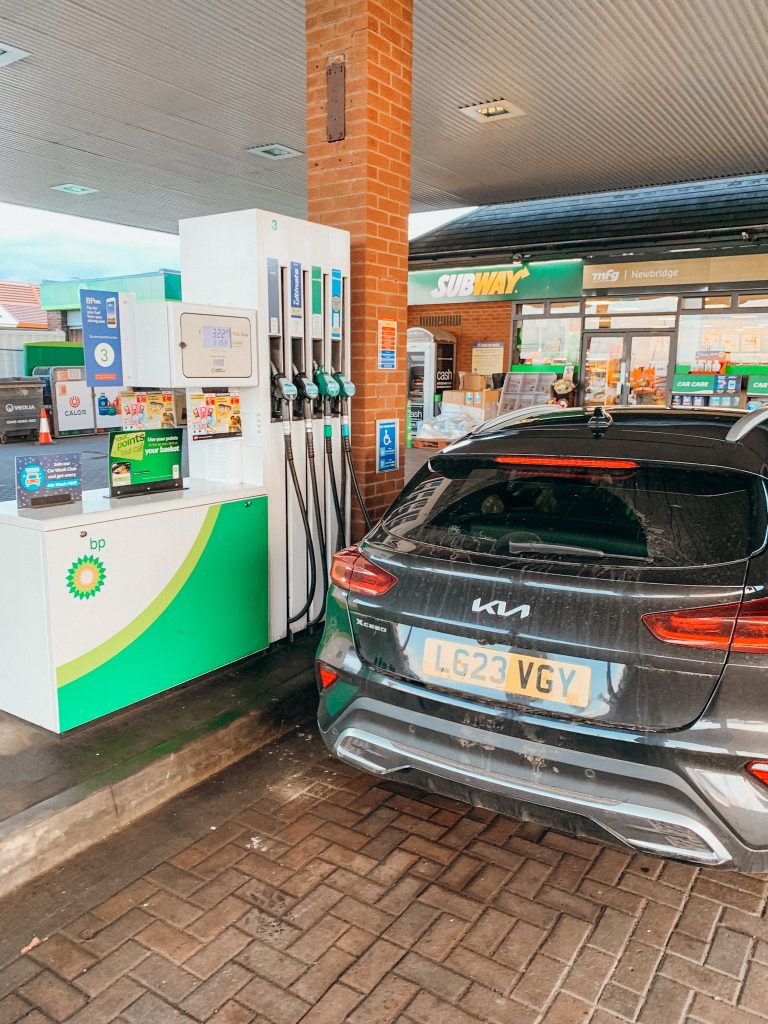 Black car parked next to a white gas pump at a gas station