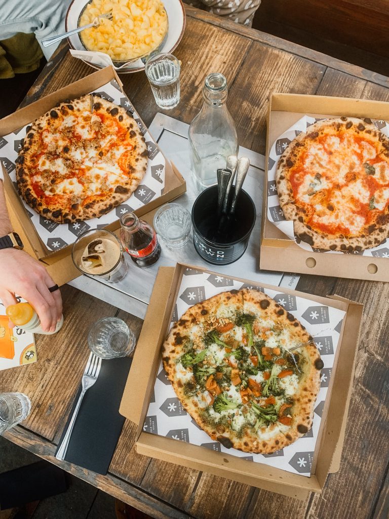 Three boxes of pizza open on a wooden table