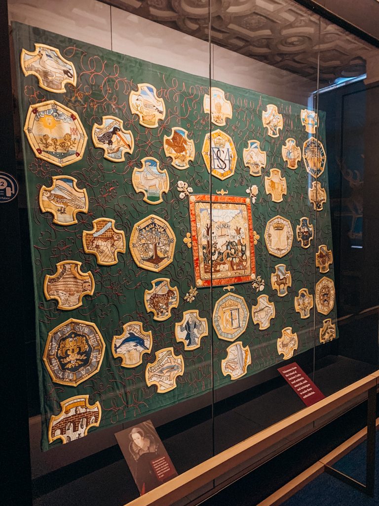 Green tapestry with yellow, embroidered icons covering it