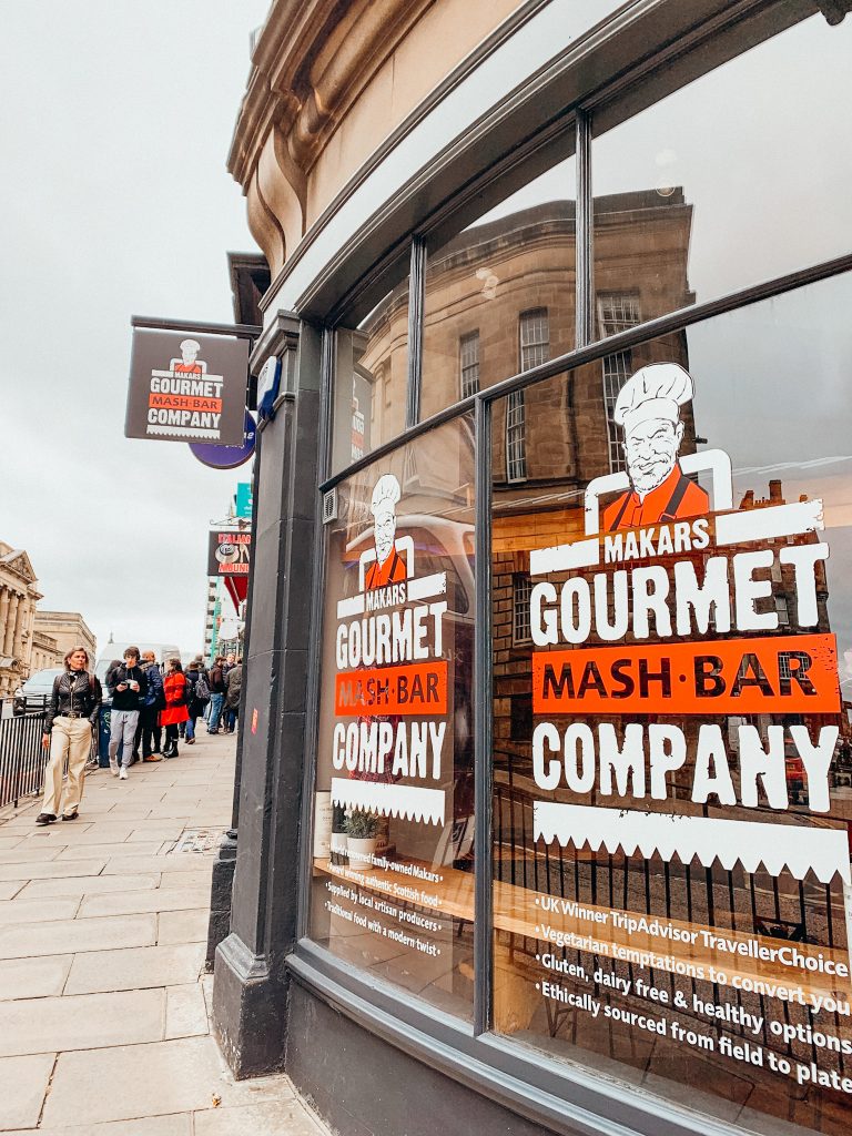Window with a black window frame with red and white words that read 'Makars Gourmet Mash Bar Company'
