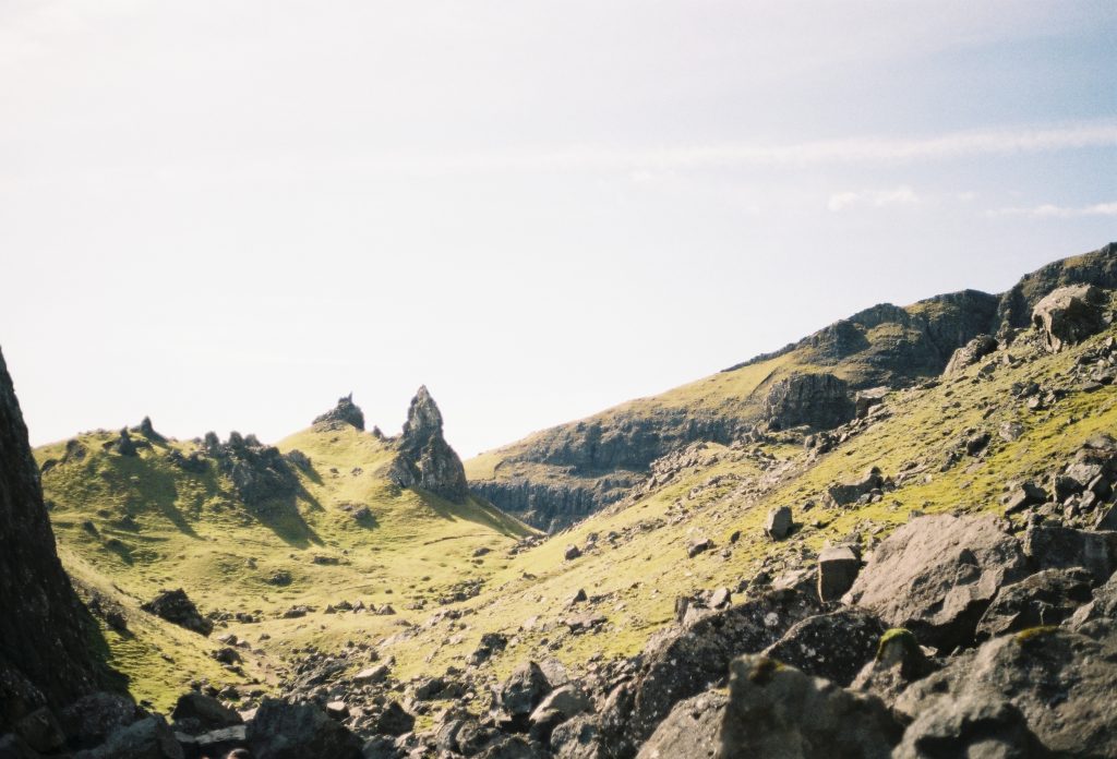 The Old Man of Storr has black boulders on green cliff and is one of the best things to do on the Isle of Skye with kids
