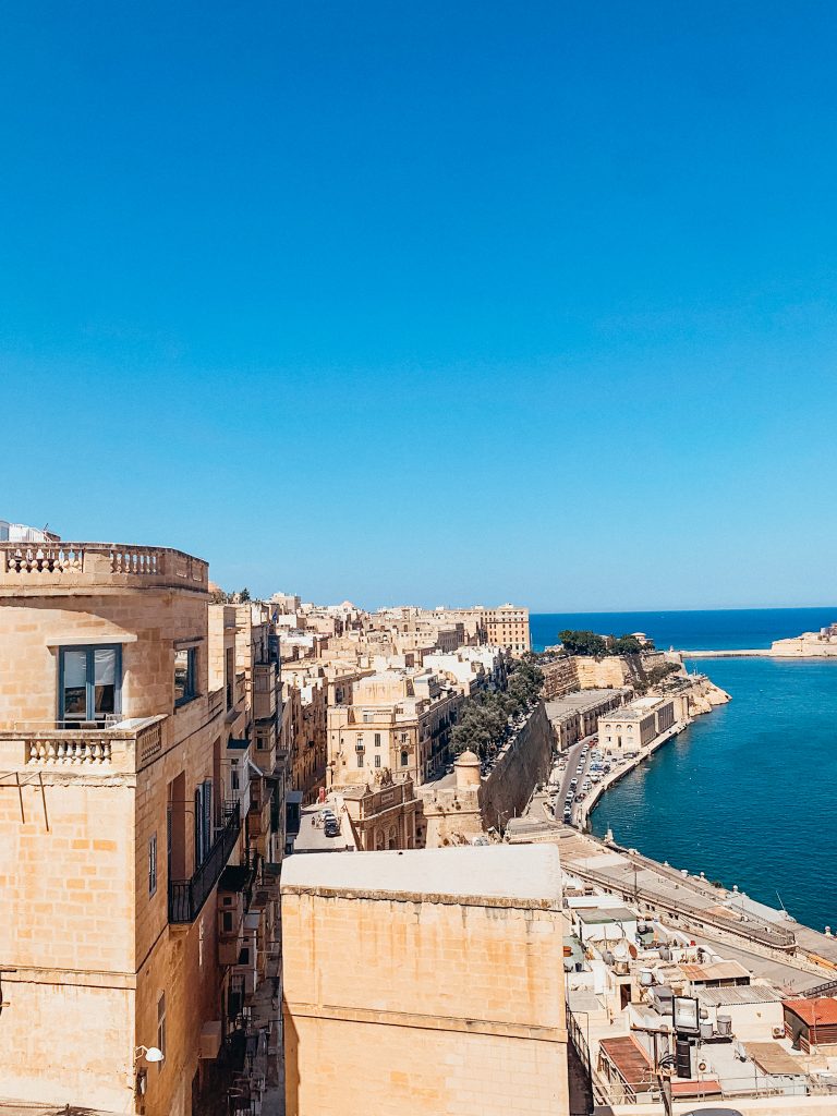 Old, stone buildings of large city line an old harbour