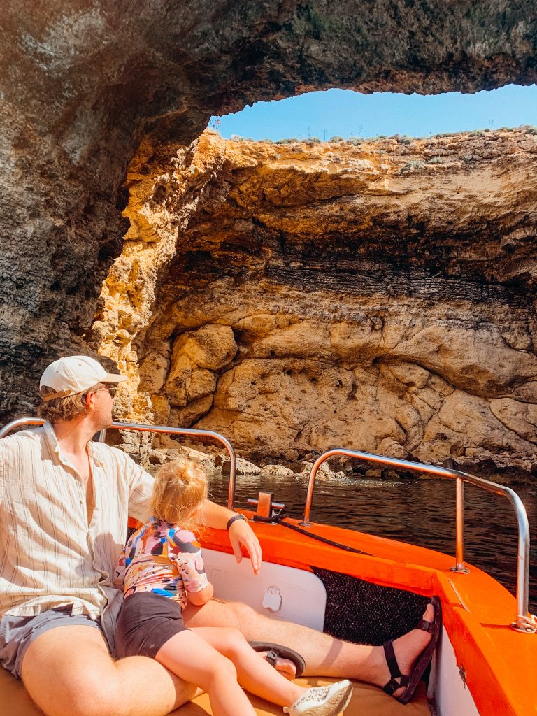 Father and child look up at hole in a cliff from a boat