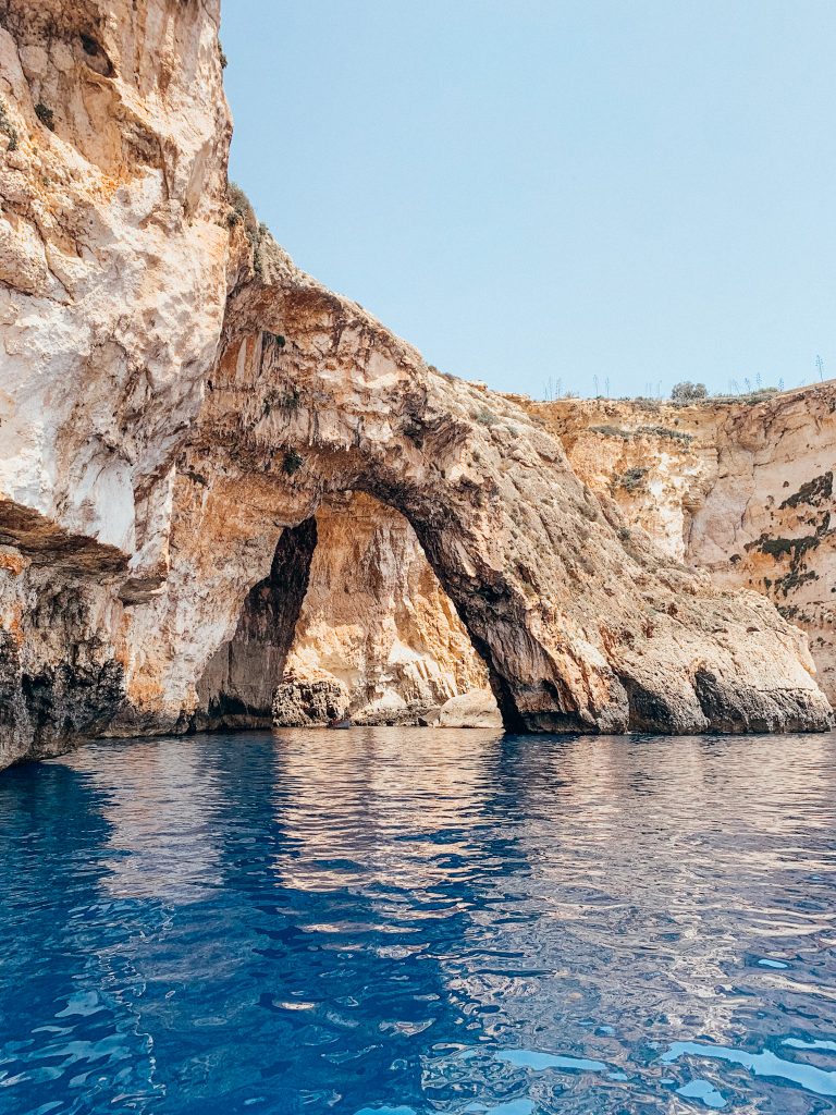 White cliffs and huge rock arch stand in dark blue sea water