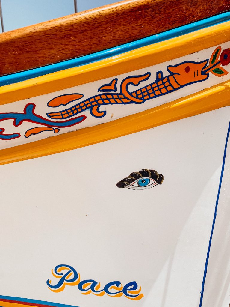 Close up image of a white boat with yellow trim and an eye painted on the side