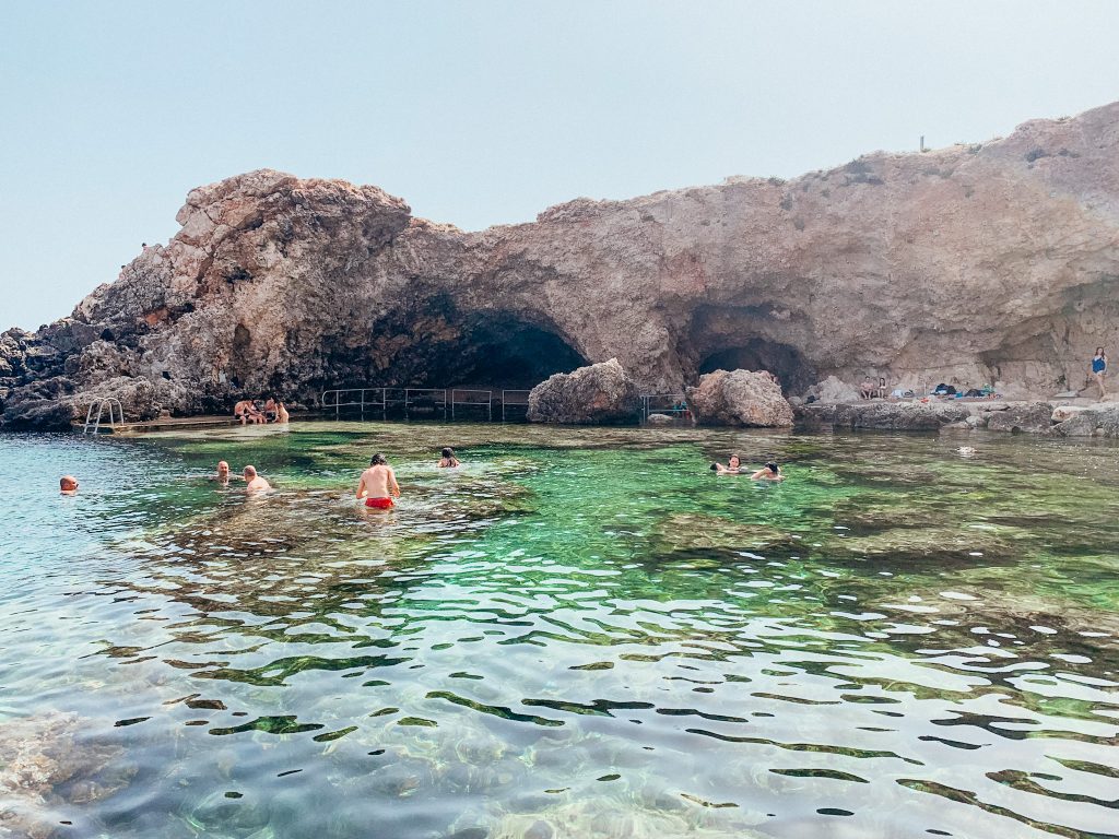 Cove with bright green water surrounded by cave and walking path