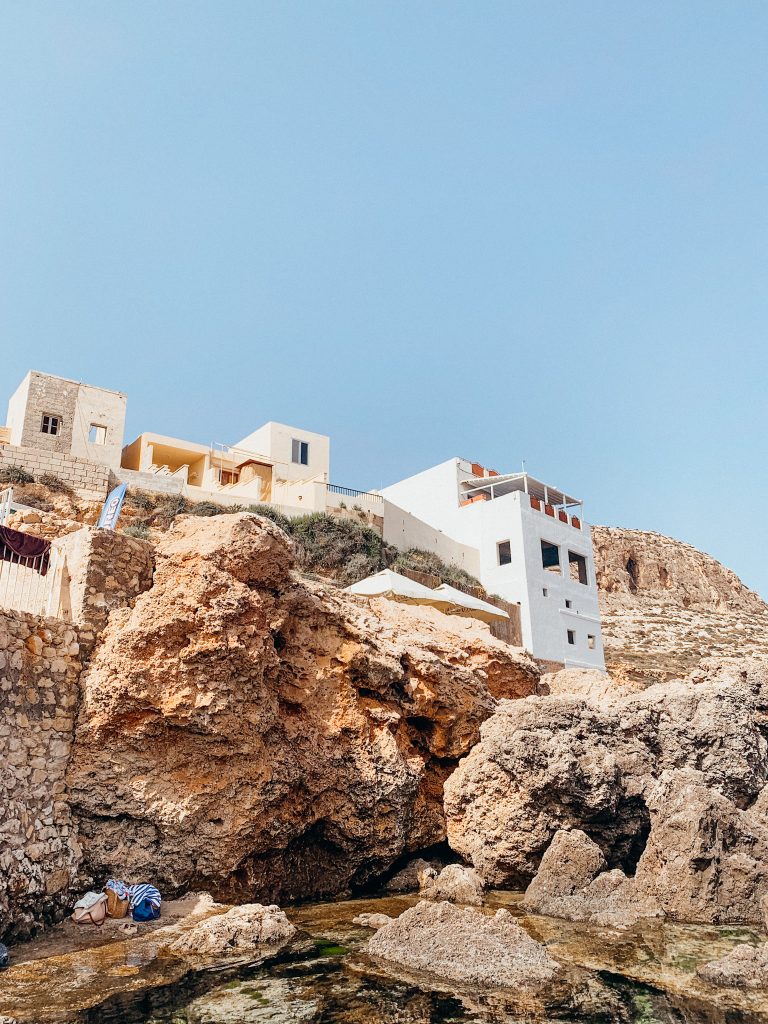 Square, white building rests on orange cliffs