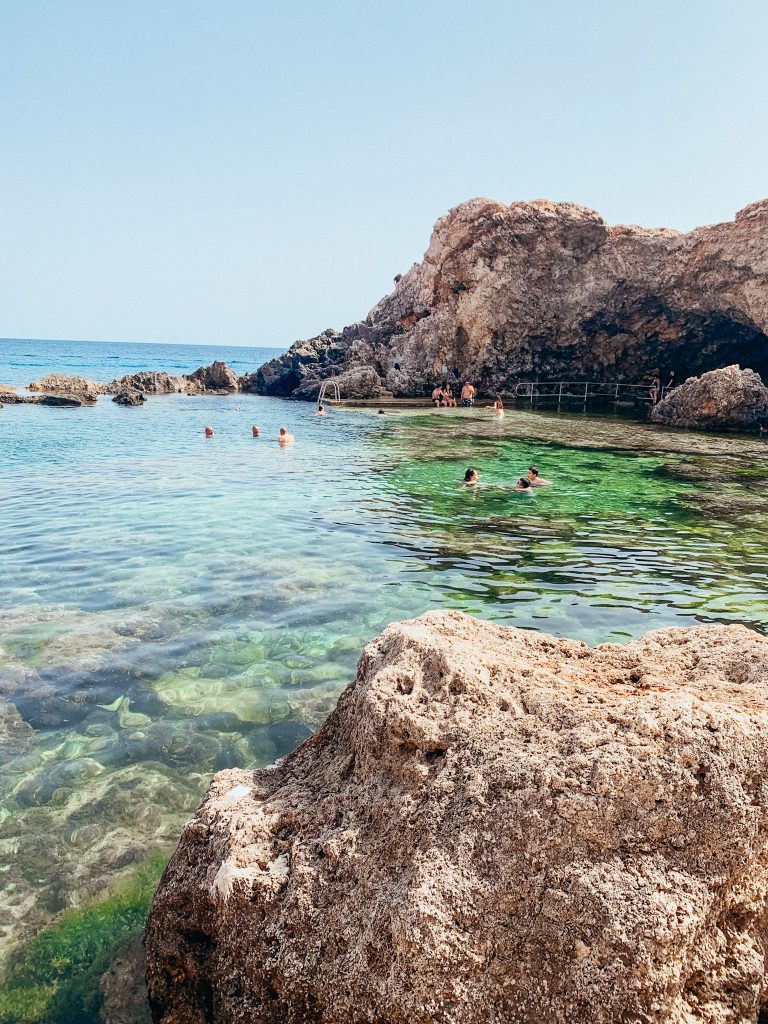 Large rocks and cave surround bright green cove