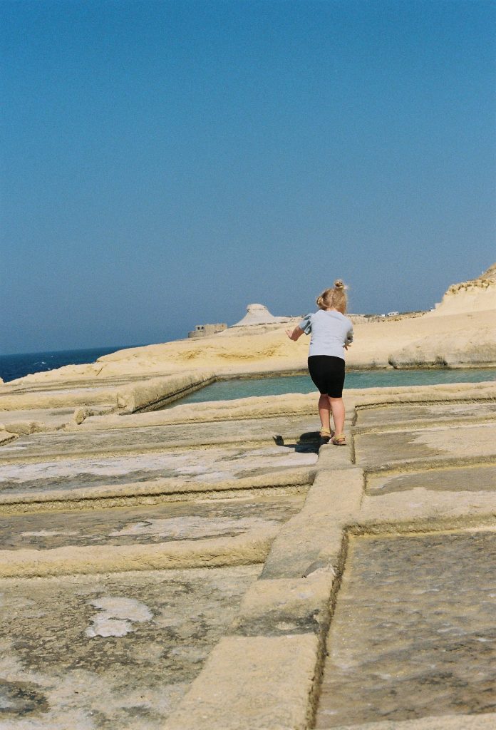 Child runs on carved rock next to the sea