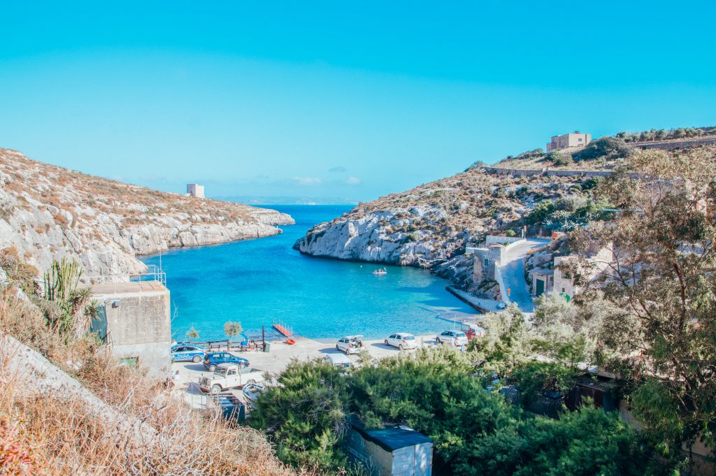 Blue bay surrounded by white cliffs covered in green and brown plants