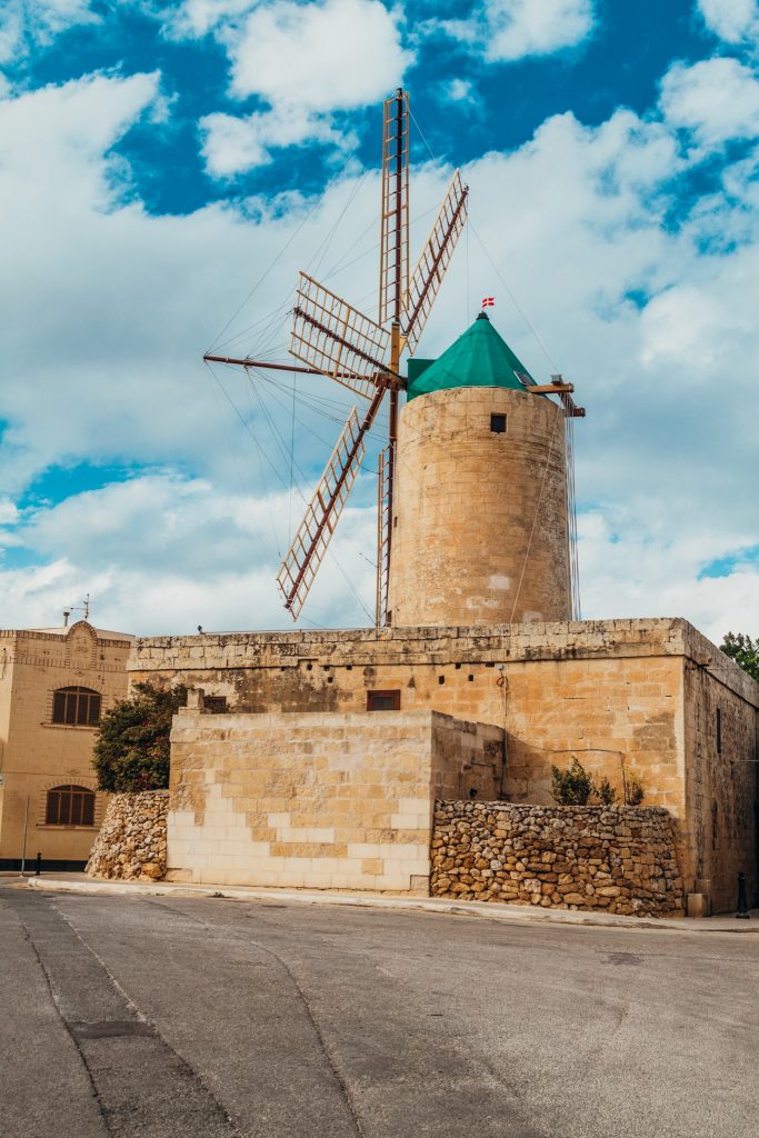 Large tan windmill with wooden blades and green roof