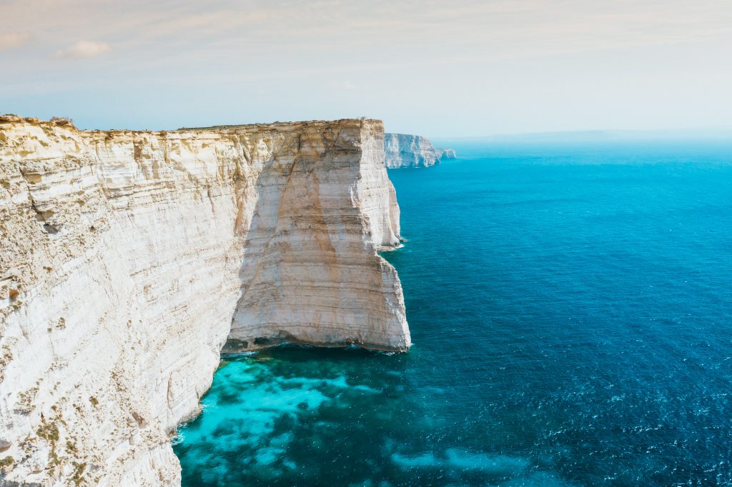 Huge white cliffs lead down to bright turqouise water