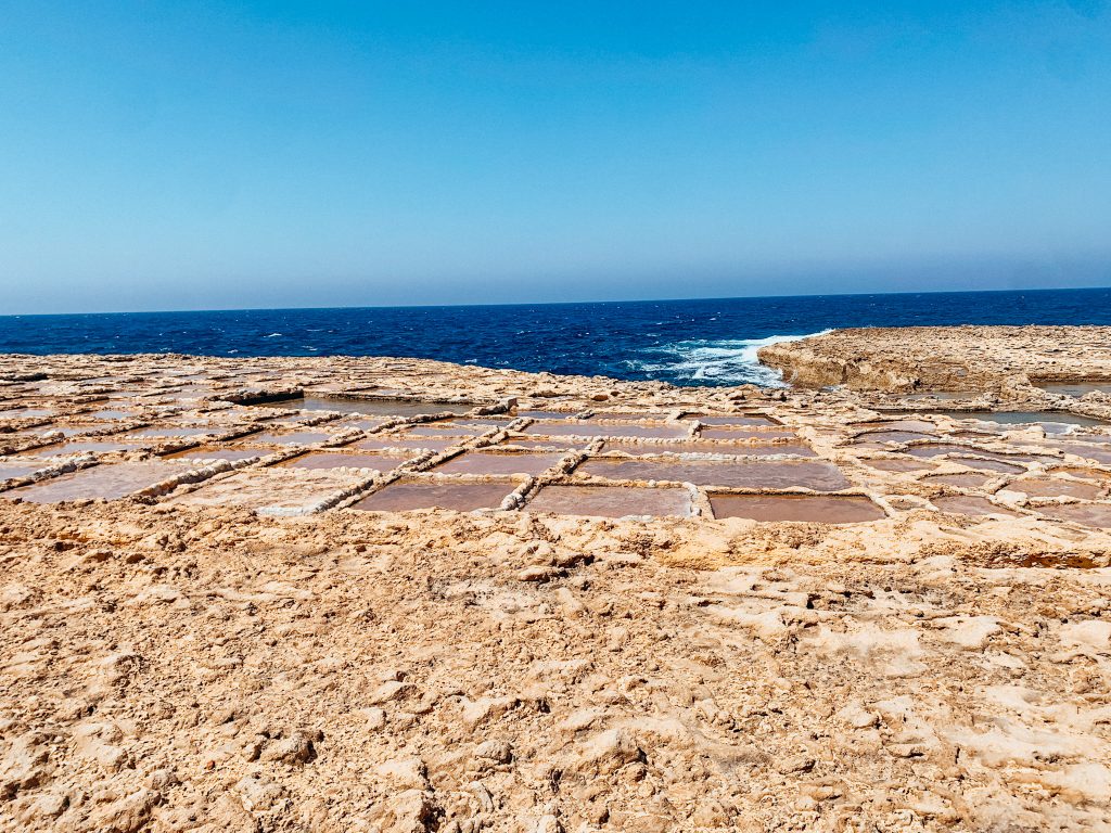 Carved square rocks full of water next to the sea