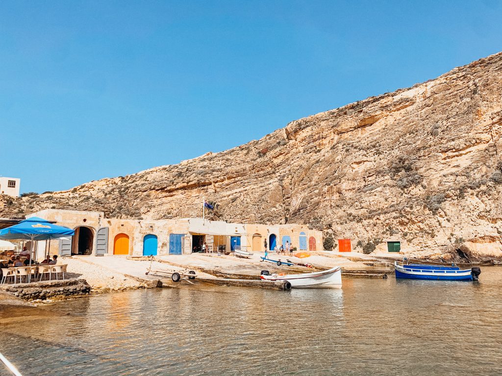 Colorful boathouse doors line water with boats docked in front