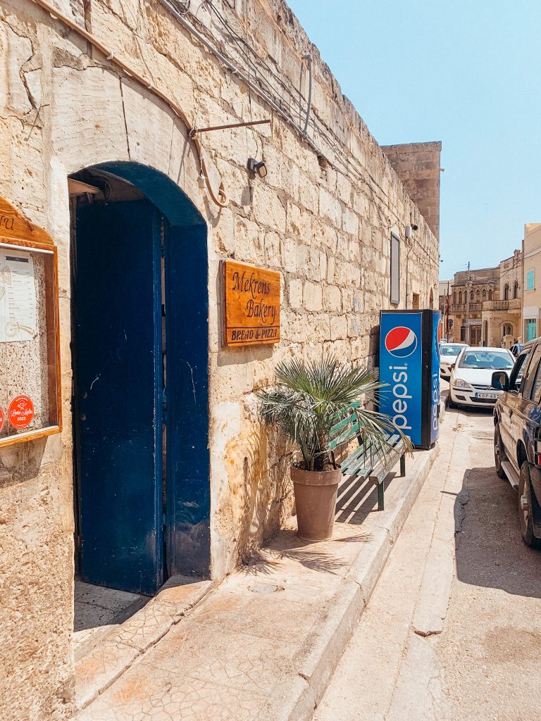 Tan building with blue door and sign that reads 'Mekrens Bakery'