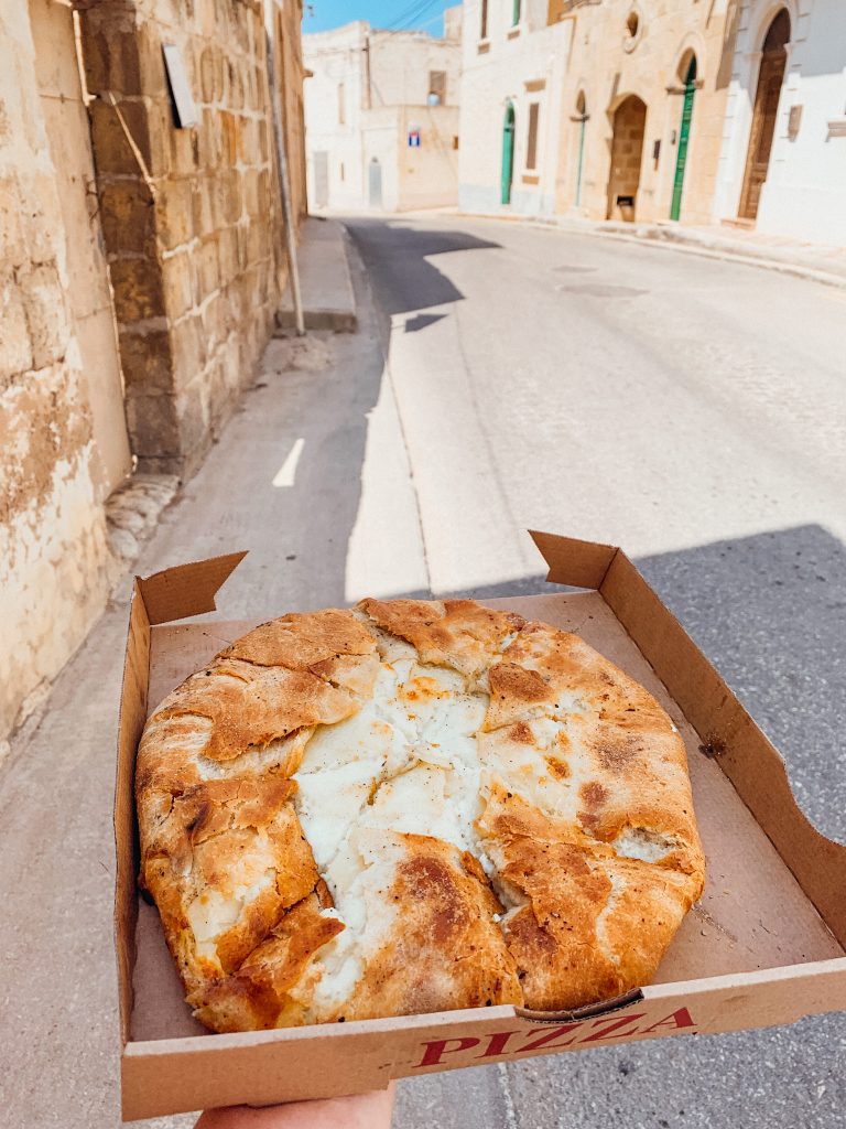 Hand holds brown box with round savoury pastry